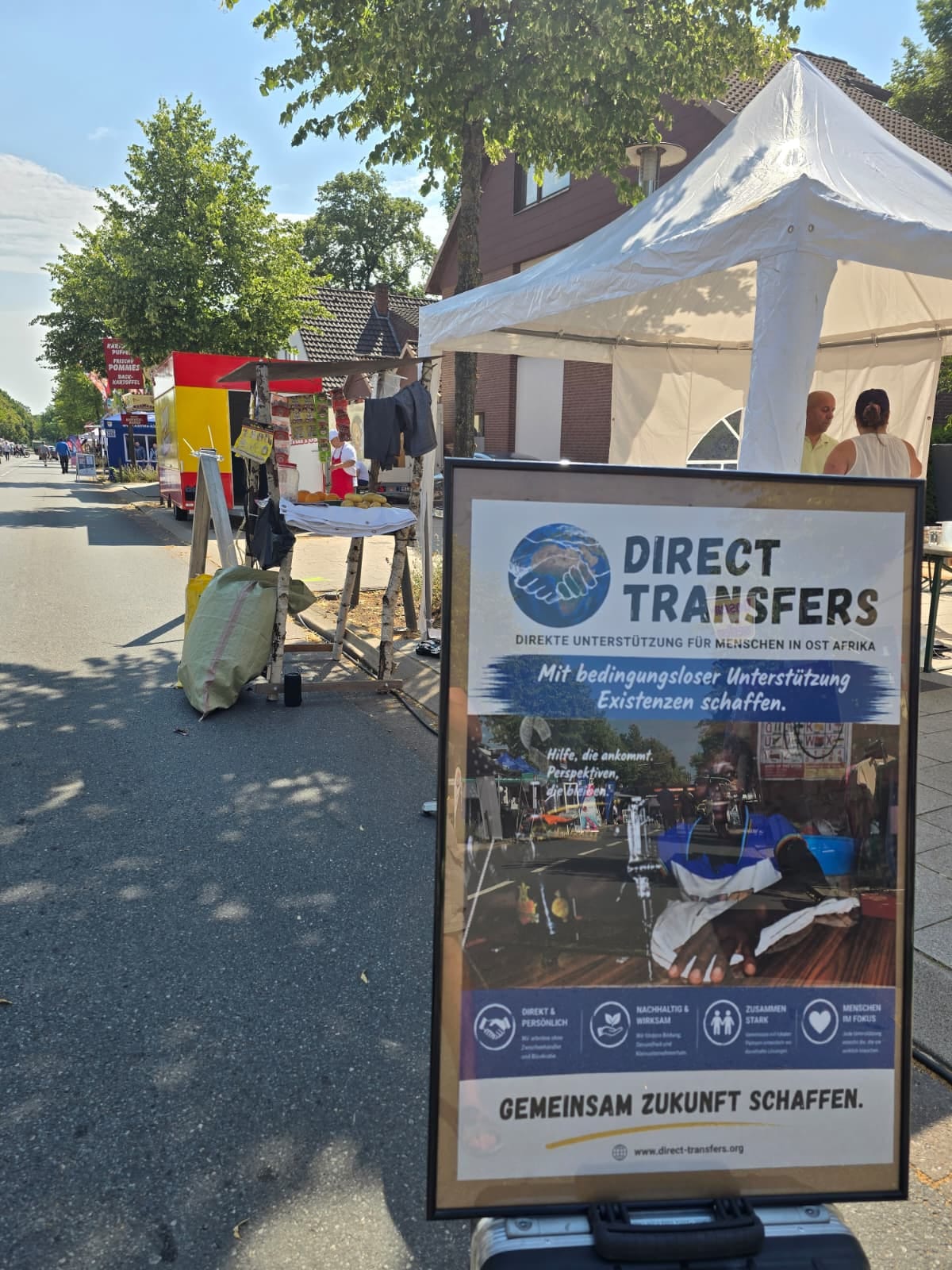 Plakat von Direct Transfers e.V. an einem Infostand beim Sommerfest